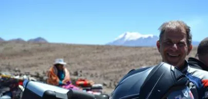 eb1d7003c8e6df756d2d2496e82e364b482d70a1 Homem sorrindo com capacete em paisagem montanhosa árida.