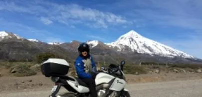 eb1d7003c8e6df756d2d2496e82e364b482d70a1 Motociclista em estrada com montanha nevada ao fundo.