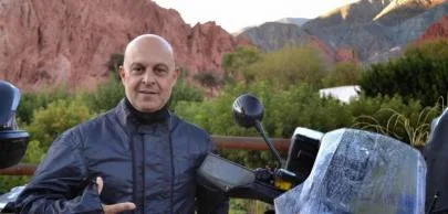 eb1d7003c8e6df756d2d2496e82e364b482d70a1 Homem careca com jaqueta preta ao lado de motocicleta.