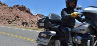 Motociclista em estrada deserta com montanhas ao fundo.