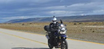 Motociclista em estrada deserta sob céu nublado.