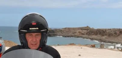 eb1d7003c8e6df756d2d2496e82e364b482d70a1 Homem de capacete preto em frente ao mar e rochas.