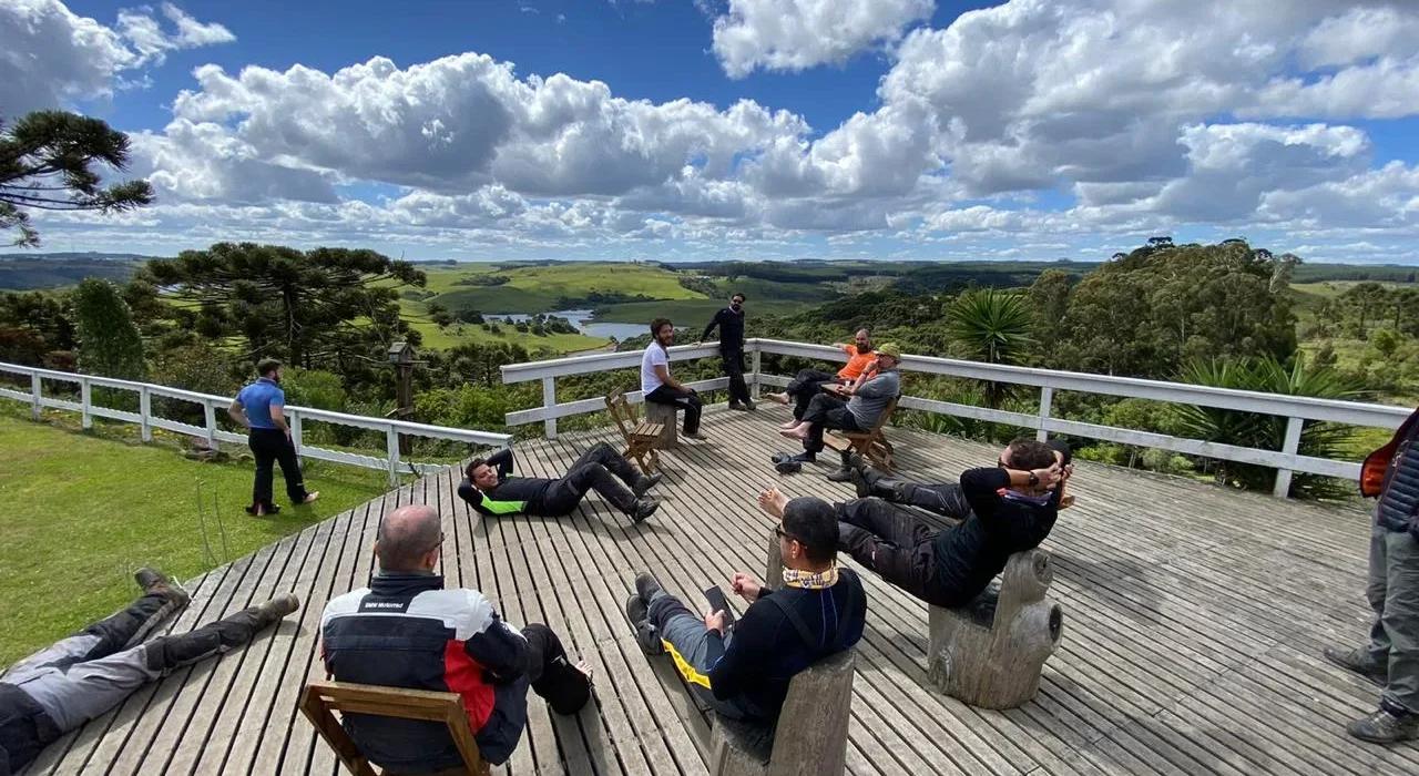 Pessoas relaxando em deck de madeira com vista panorâmica.