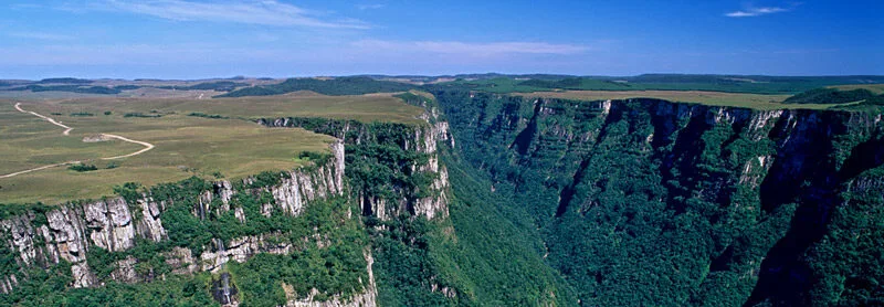 Cânion verde com penhascos altos e céu azul claro.