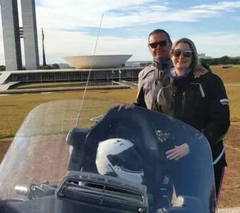 Casal em frente ao Congresso Nacional com motocicleta.