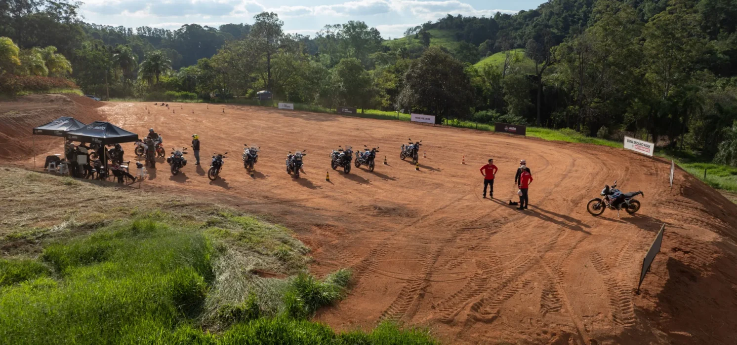 Pista de terra com motos e instrutores ao ar livre.