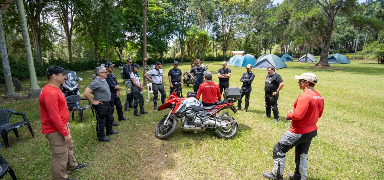 Grupo de motociclistas em treinamento ao ar livre com instrutor.